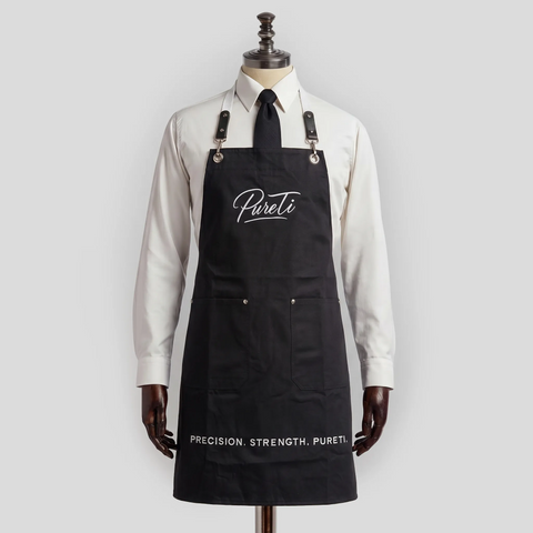 Black apron with 'Pureti' branding on a mannequin against a white background