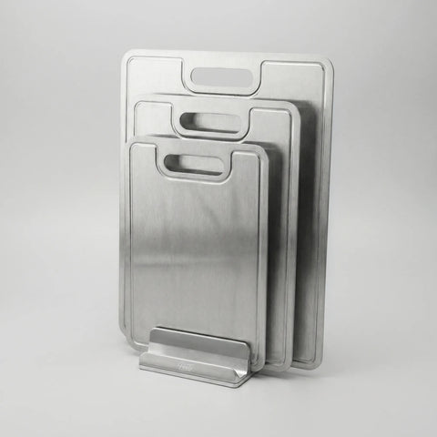 Set of titanium cutting boards with handles on a gray background