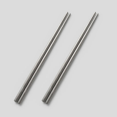 Two PureTi titanium chopsticks on a light gray background