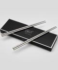 Pair of PureTi titanium chopsticks on a black box with 'PureTi' branding on a light gray background
