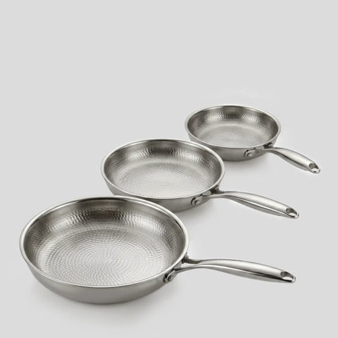 Three PureTi titanium hammered frying pans in three sizes on a light gray background