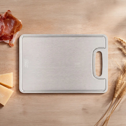 Titanium cutting board on a wooden surface with meat and cheese.