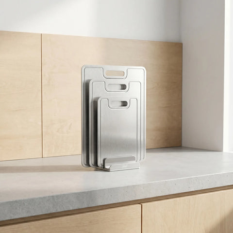 Set of titanium cutting boards on a kitchen counter with wooden cabinets in the background.