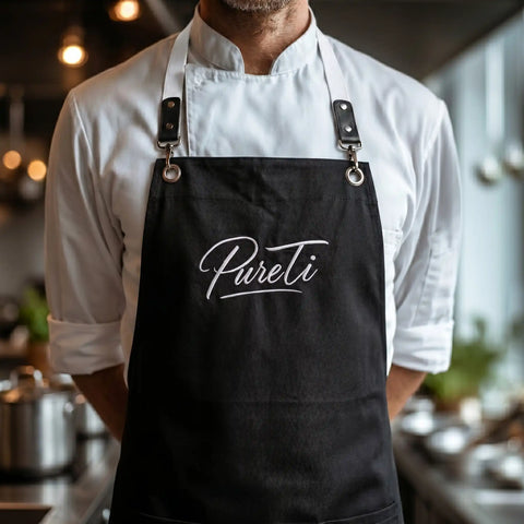 Person wearing a black apron with 'PureTi' logo in a kitchen setting