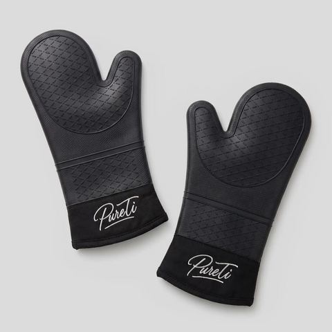 Pair of black PureTi silicone oven mitts with embroidered logo on a light gray background