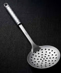 PureTi titanium slotted spoon on a black fabric background