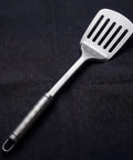 Titanium slotted spatula on a black background