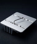 Underside of the PureTi aluminium cutting board stand showing the base plate on a black fabric background