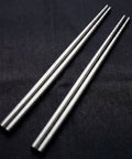 Two pairs of PureTi titanium chopsticks on a black fabric background