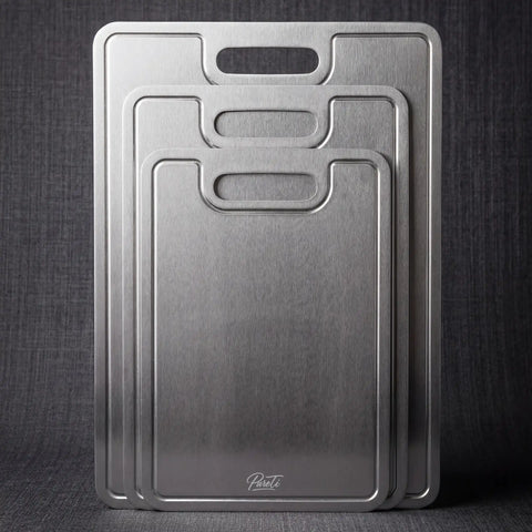 Three PureTi titanium cutting boards standing upright against a dark gray fabric background