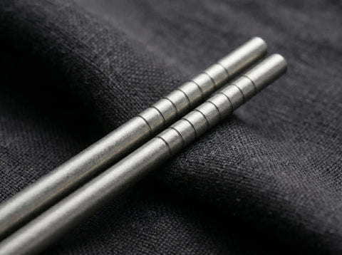 Titanium chopsticks on a dark fabric background