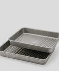 Two PureTi titanium baking trays stacked, angled view on a light gray background