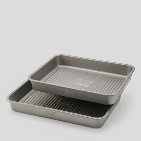 Two PureTi titanium baking trays stacked, angled view on a light gray background
